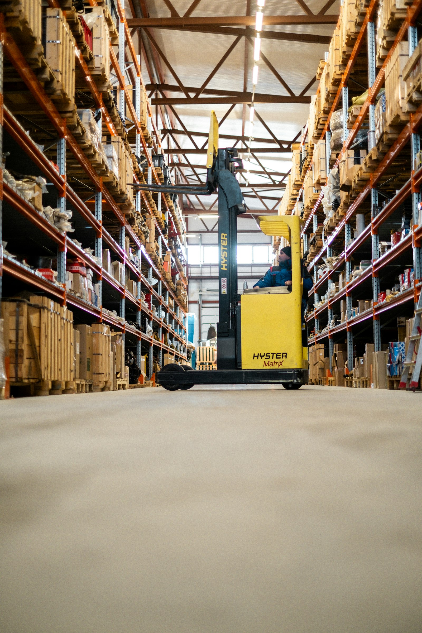 Reach-truck moving stock down the aisle of a fully racked equipment warehouse